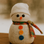 Bonhomme de neige fabriqué à partir d’une chaussette blanche, décoré avec une écharpe en tissu et des boutons colorés