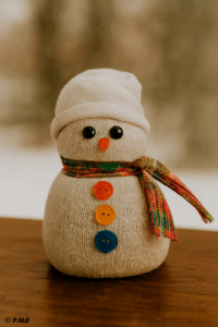 Bonhomme de neige fabriqué à partir d’une chaussette blanche, décoré avec une écharpe en tissu et des boutons colorés