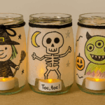 Trois lanternes Halloween décorées par des enfants avec des personnages : sorcière, squelette et monstre à trois yeux