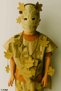 Enfant portant un costume DIY d’automne avec masque végétal, feuilles en kraft, mots doux et éléments naturels.