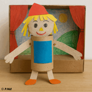 Marionnette artisanale en rouleau de papier toilette devant un théâtre en carton décoré