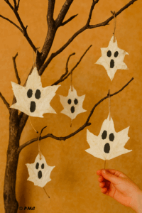 Main d’enfant tenant une feuille d’érable peinte en fantôme pour Halloween