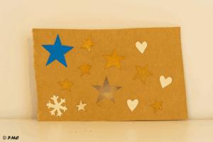 Bande de papier kraft décorée avec des étoiles, cœurs et flocons découpés grossièrement par un enfant