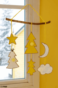 Suspension de Noël accrochée près d’une fenêtre, baignée de lumière hivernale