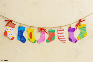 Guirlande de chaussettes de l’Avent en papier, décorée avec des rubans et des grelots, réalisée par un enfant