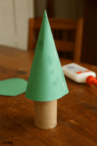 Cône en papier vert collé sur un rouleau de carton, étape de fabrication d’un sapin de Noël