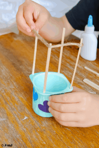 Mains d’enfant décorant un pot de yaourt pour fabriquer le panier d’une montgolfière