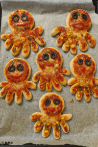 Mini pizzas pieuvres dorées décorées avec des légumes, réalisées par des enfants
