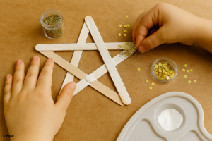 Mains d’enfant saupoudrant des paillettes dorées sur une étoile en bois