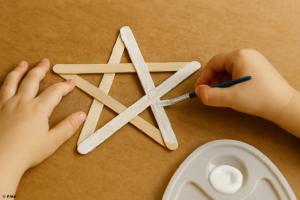 Main d’enfant peignant une étoile en bâtonnets de glace avec un pinceau